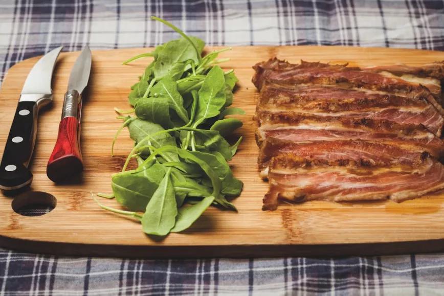 Secreto ibérico cortado en lonchas y servido con rúcula sobre una tabla de madera