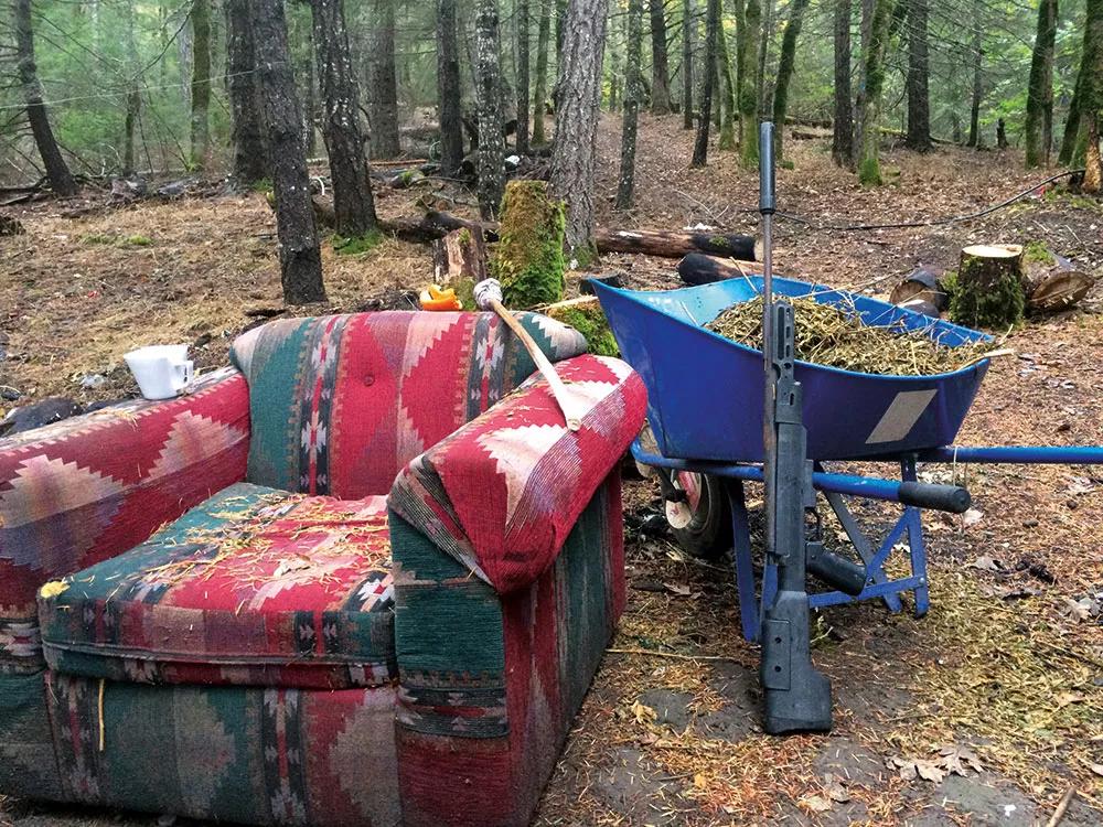 Sofá de guardia junto al rifle de asalto y restos de plantas en la carretilla.