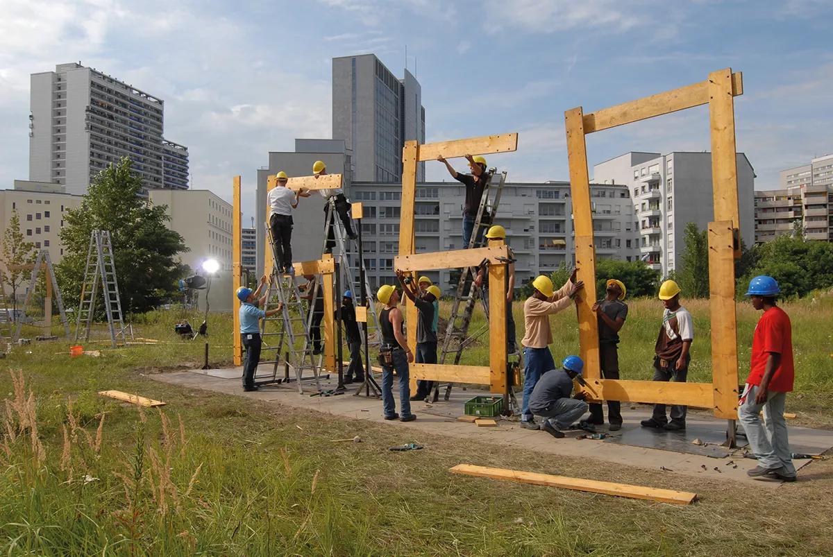 Standard time, obra de Mark Formarek en la que unas personas construyen el tiempo a medida que avanza. Durante 24 horas, cambian meticulosamente los dígitos de una gran instalación, minuto tras minuto, en un reloj ubicado en un solar. Fotografía de Bernd Schuller.