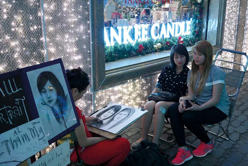 Dos chicas posando para un retratista callejero en Ho Chi Minh.