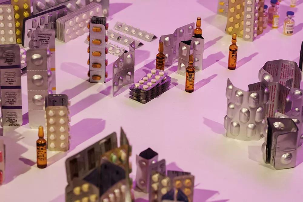 Como dicen los comisarios de la muestra: “La instalación Say yes! (2022) de Julia Montilla (Barcelona, 1970) visibiliza aspectos de la espacialización de las drogas al disponer,  en forma de mapa tridimensional sobre una mesa, los blísteres aportados por personas de su entorno social. En ella la ciudad es una máquina de producción donde lo psicofármacos  son los eslabones que conectan la materialidad de los cuerpos con la abstracción del cibercapital.”