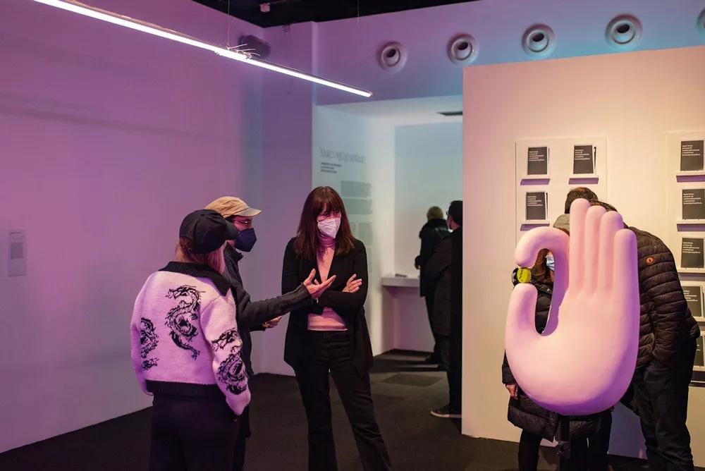 Una imagen de la inauguración de Narcohumanismo en el Bòlit, con Eloy Fernández Porta y Núria Gómez Gabriel (de espalda) explicando una de las obras.
